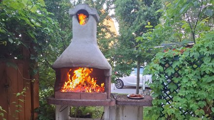 Ein gemauerter Griller im Garten mit brennenden Holzscheiteln
