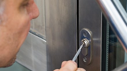 Nahaufnahme der Hand eines männlichen Schlossknackers beim Reparieren eines Türgriffs zu Hause.