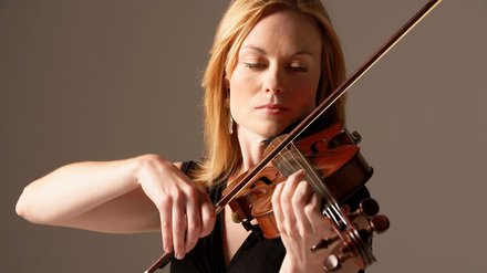 Symbolbild Musikinstrumentenversicherung: Frau spielt Geige.