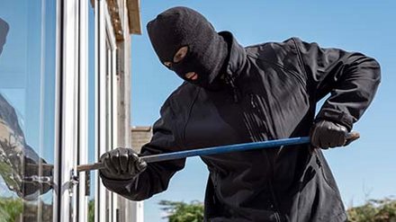 1970948588 Einbrecher der mit einem Brecheisen in ein Haus einbricht