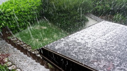 1581611494 Hagel fällt während eines Hagelsturms auf ein Hausdach
