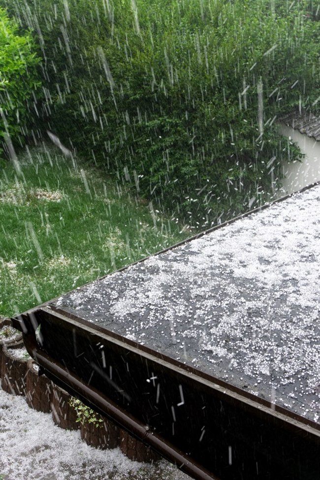 1581611494 Hagel fällt während eines Hagelsturms auf ein Hausdach