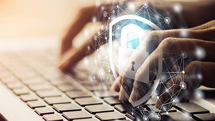 Hände tippen auf Laptop-Tastatur, darüber eingeblendet ein digitales Schloss-Symbol als Zeichen für Datensicherheit