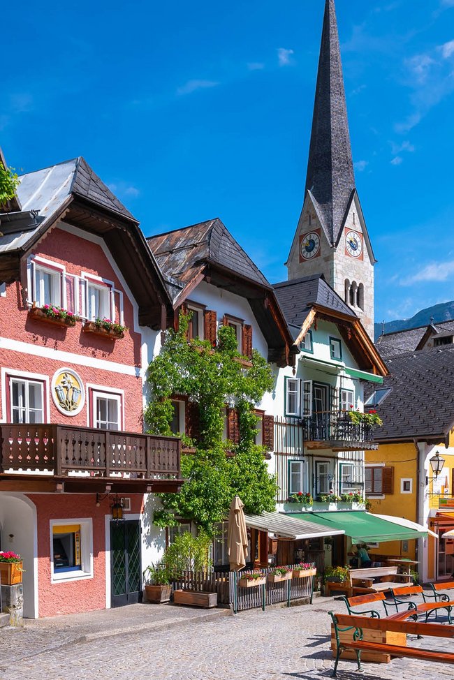 Ein Stadtplatz mit mehreren Gebäuden und einer Kirche im Hintergrund.