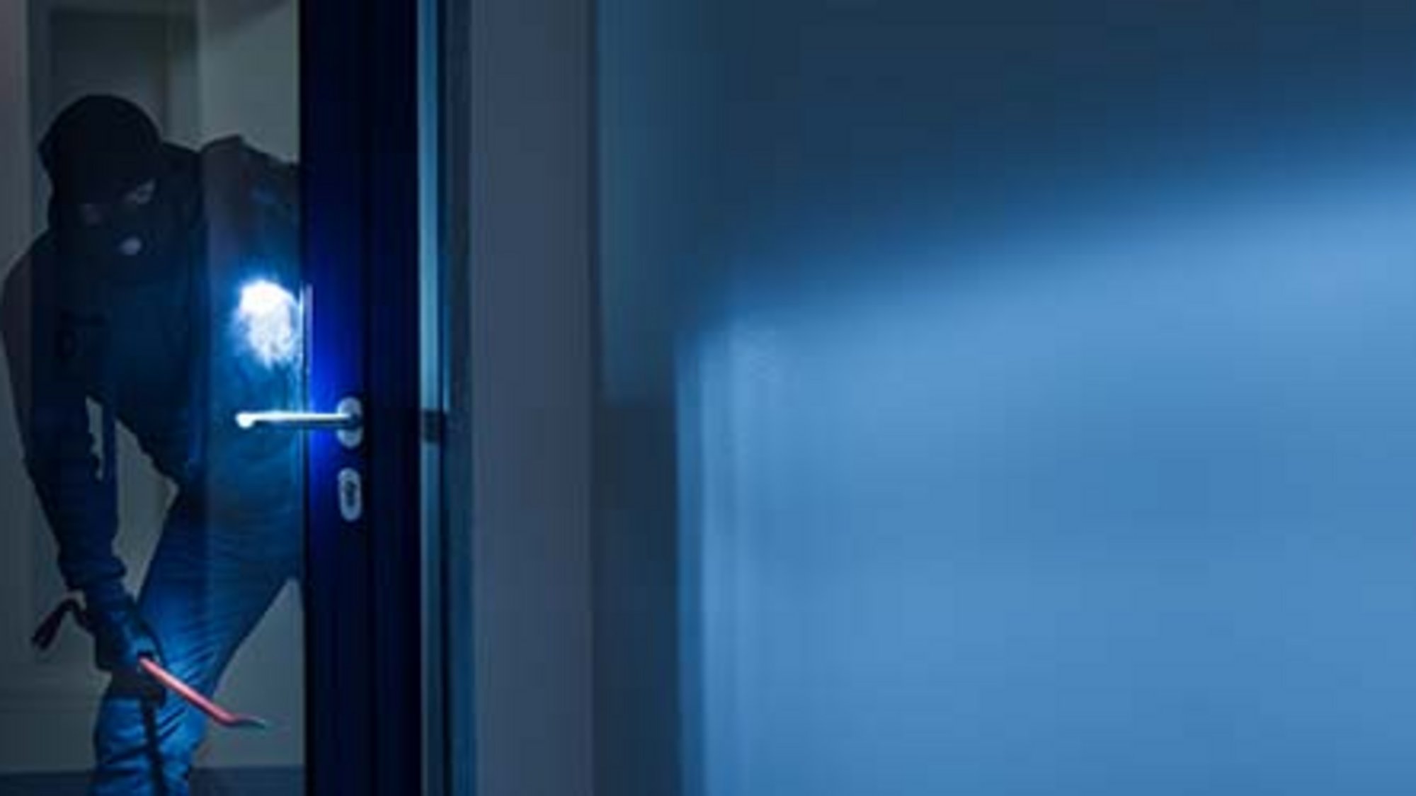 Einbrecher mit einem Brecheisen und einer Taschenlampe in der Hand