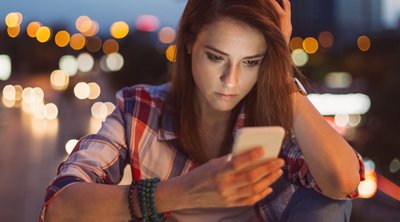 Frau sieht besorgt auf ihr Smartphone.