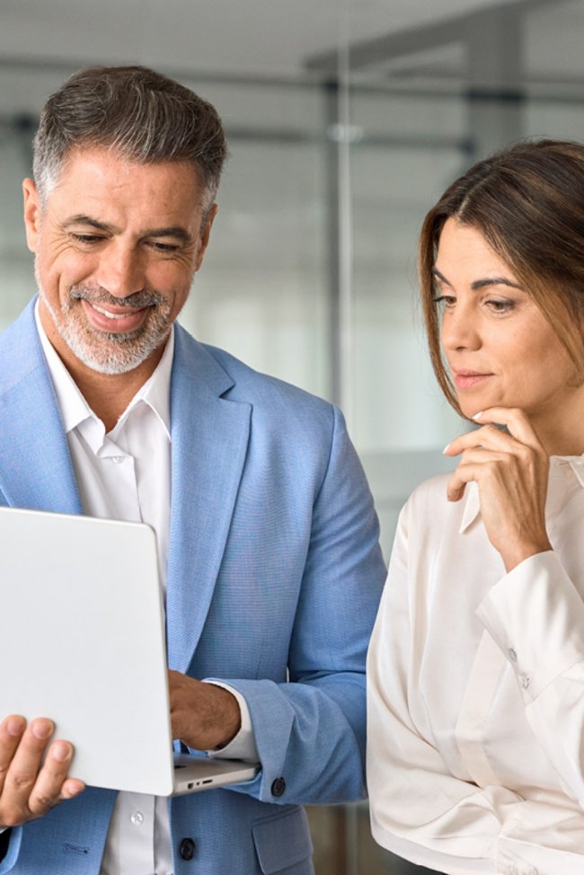 Mann und Frau blicken auf einen Laptop