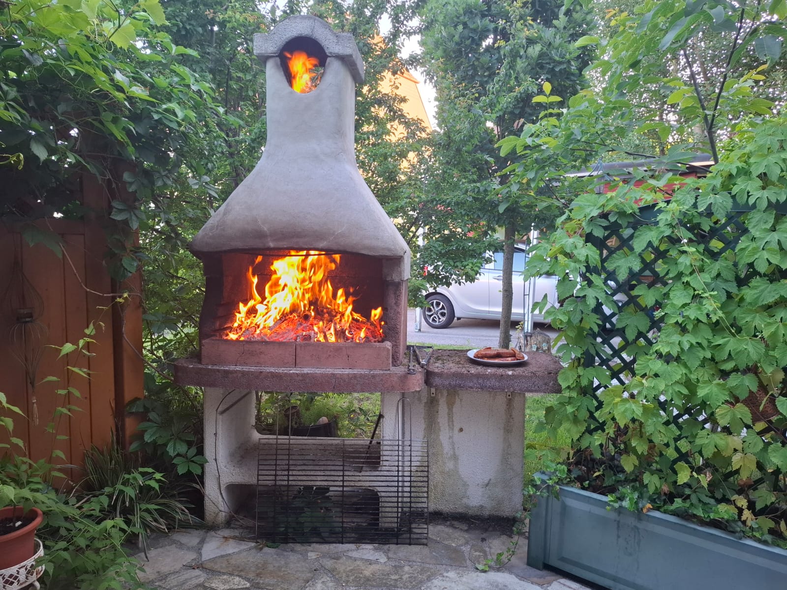 Ein gemauerter Griller im Garten mit brennenden Holzscheiteln